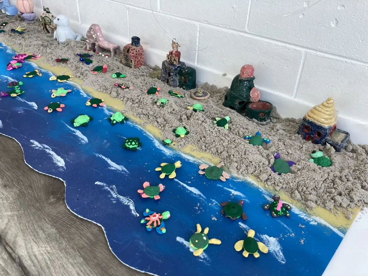 Clay turtles on a painted shoreline