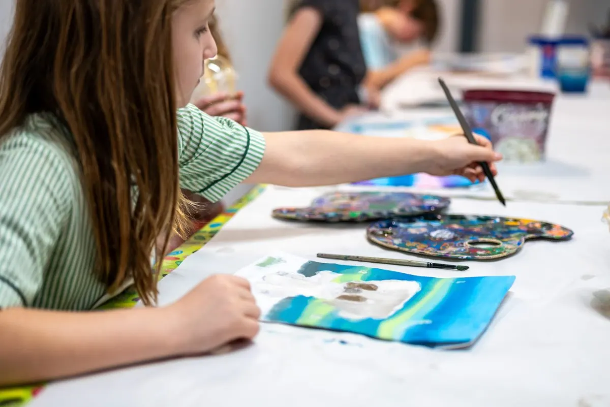 A mini-artist concentrating on a watercolour painting