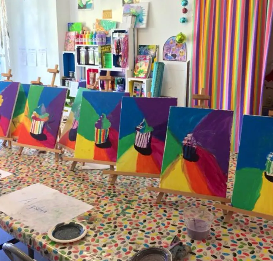 A row of cupcake paintings on easels along the party table