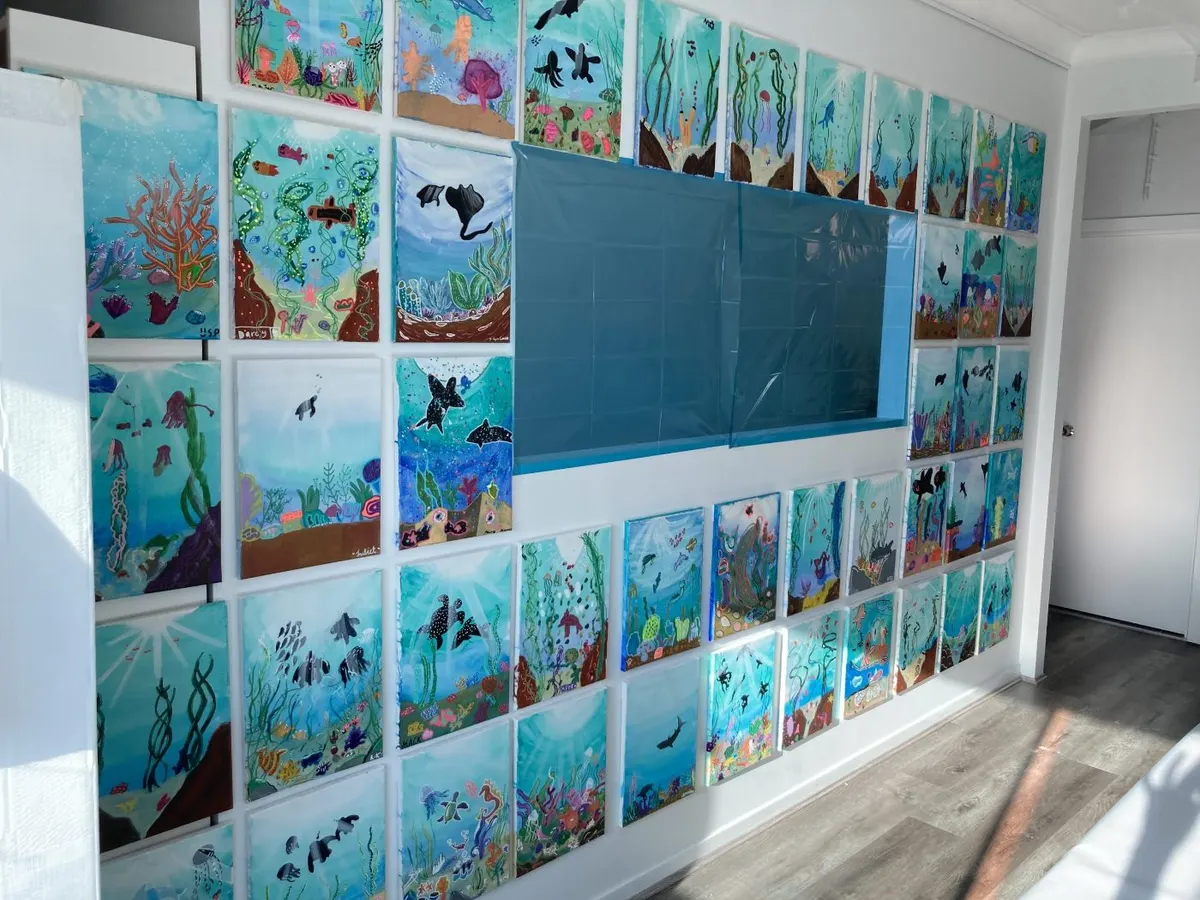 Reef paintings hung in a grid across the studio wall