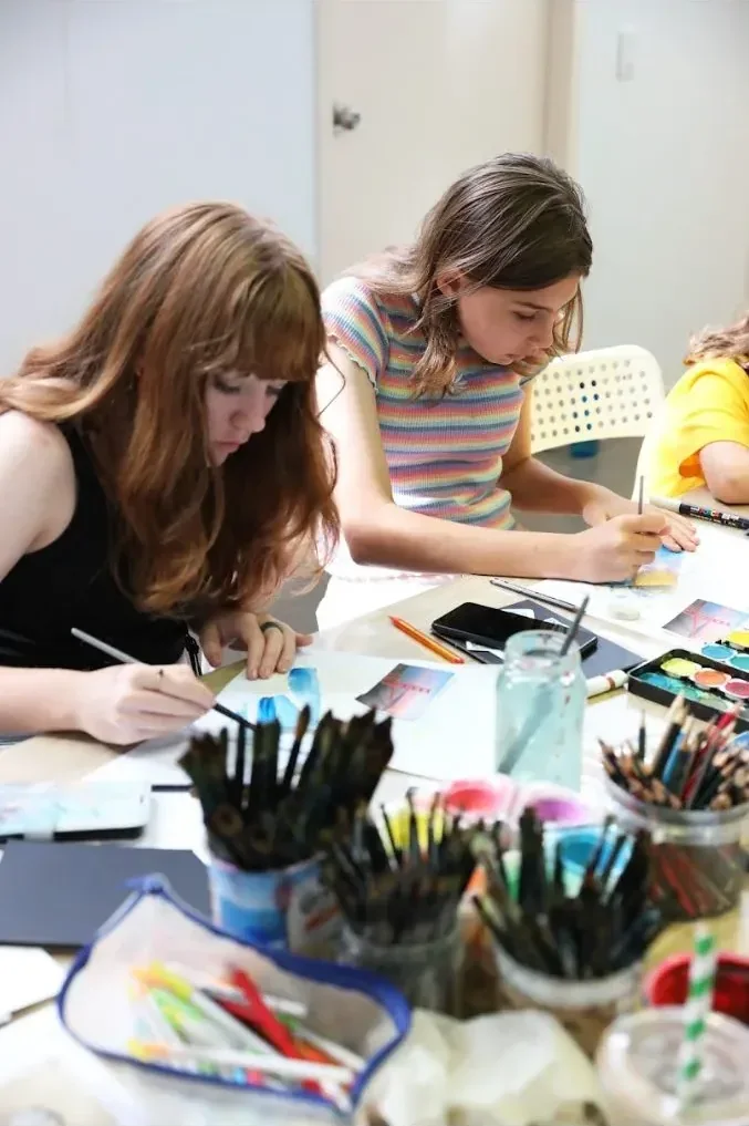 Two mini-artists concentrating on their work at the studio table