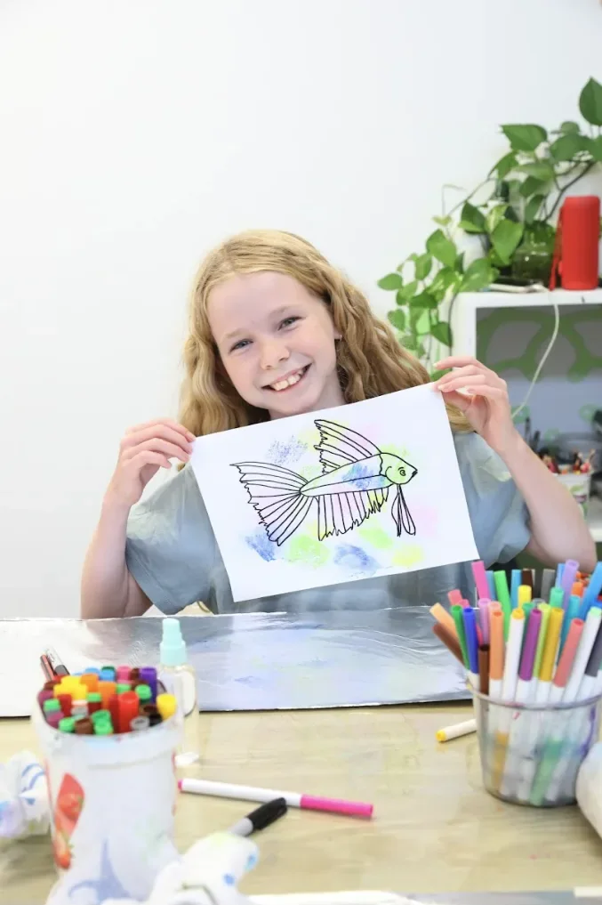 A happy mini-artist holding up their finished artwork