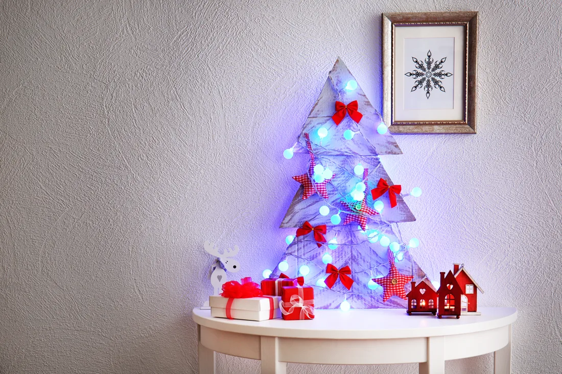 A cardboard Christmas tree decorated with bows, stars and glowing lights